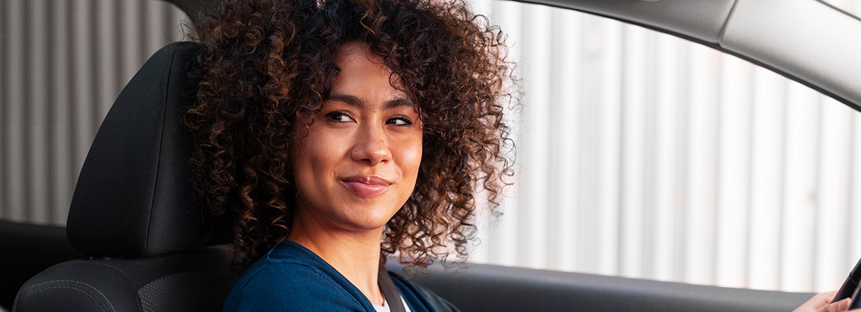 mulher com expressão satisfeita sentada dentro de um veículo automotivo